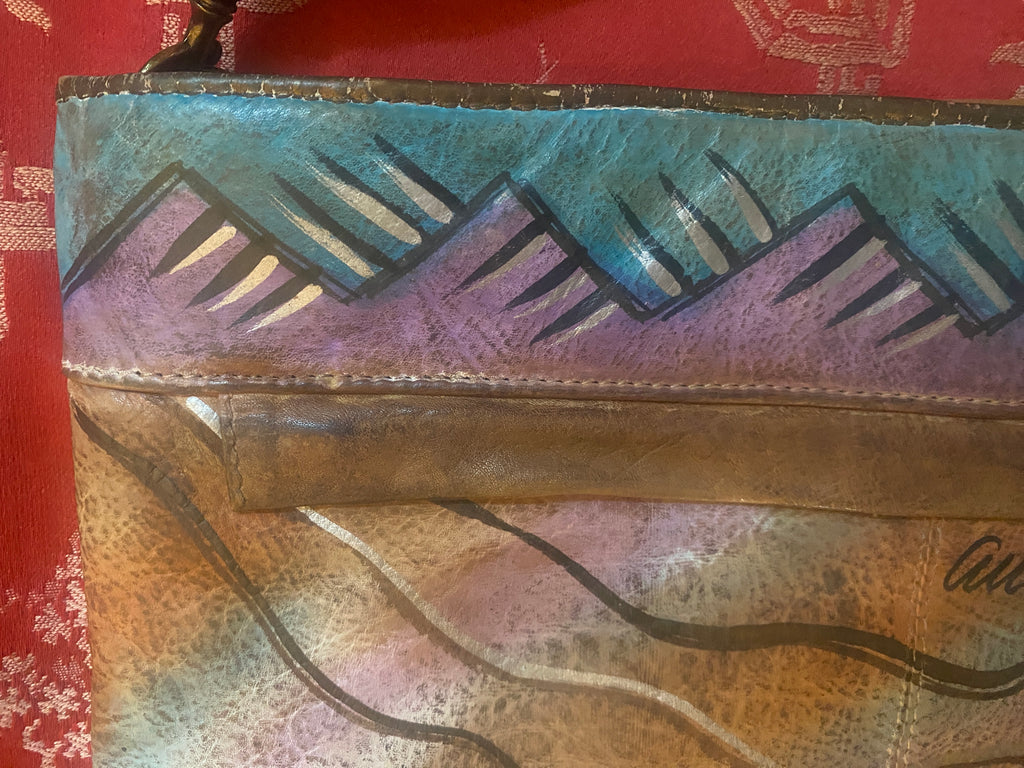 True 1980's tan hand painted clutch in purples, blues, white and black with a tribal boho vibe. Signed by designer Allan Edwards on the outside of the purse. This can be carried as a clutch by or shoulder bag by removing the strap.