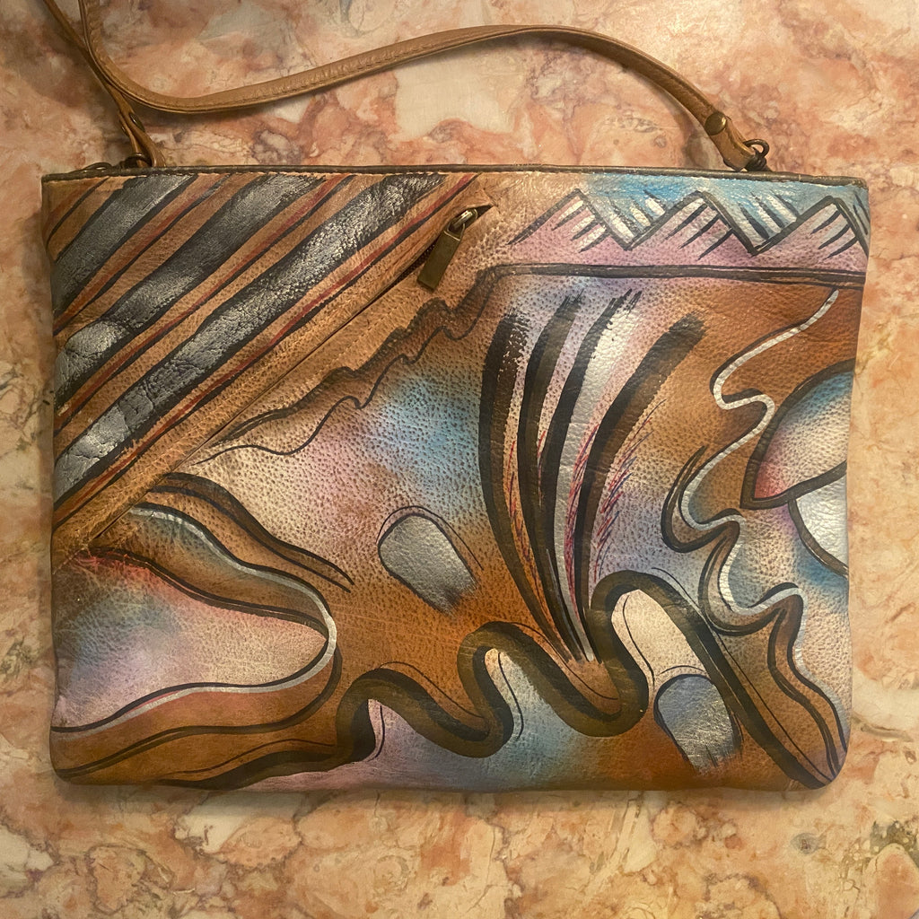 True 1980's tan hand painted clutch in purples, blues, white and black with a tribal boho vibe. Signed by designer Allan Edwards on the outside of the purse. This can be carried as a clutch by or shoulder bag by removing the strap.